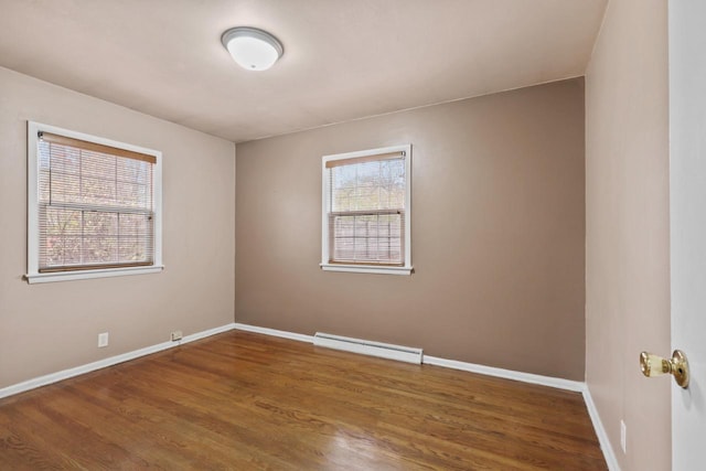 spare room featuring wood finished floors, baseboard heating, and baseboards