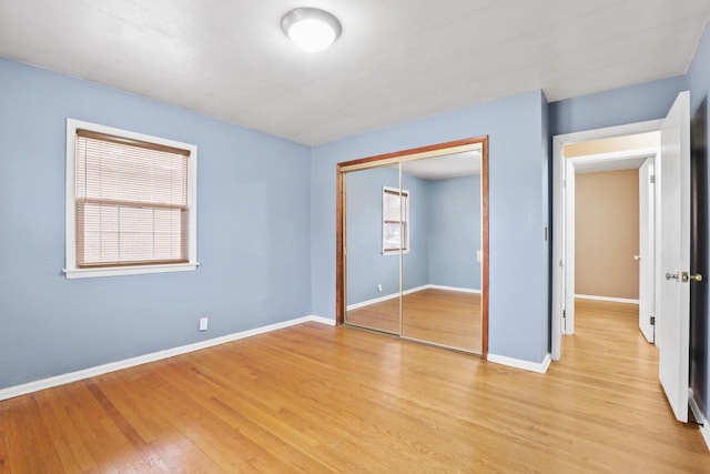 unfurnished bedroom featuring baseboards, a closet, and light wood-type flooring
