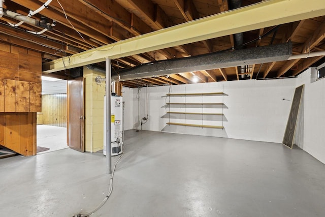 unfinished basement featuring concrete block wall, wooden walls, and gas water heater