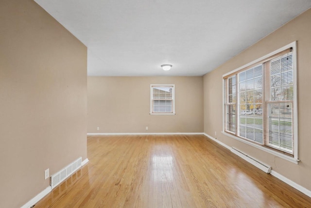 spare room with baseboards, wood finished floors, visible vents, and baseboard heating