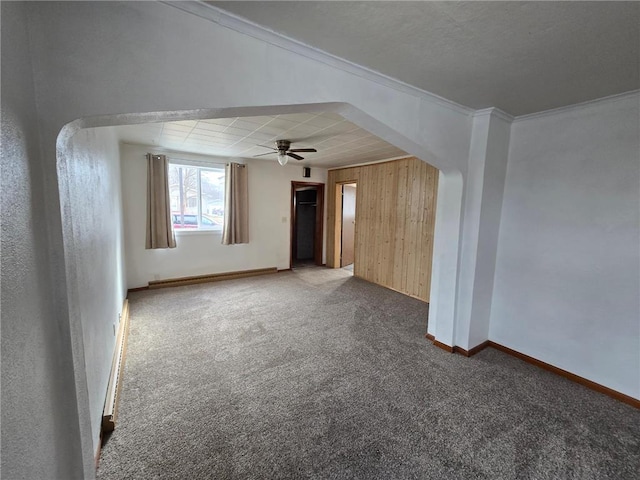 carpeted empty room with wooden walls, ceiling fan, ornamental molding, and baseboards