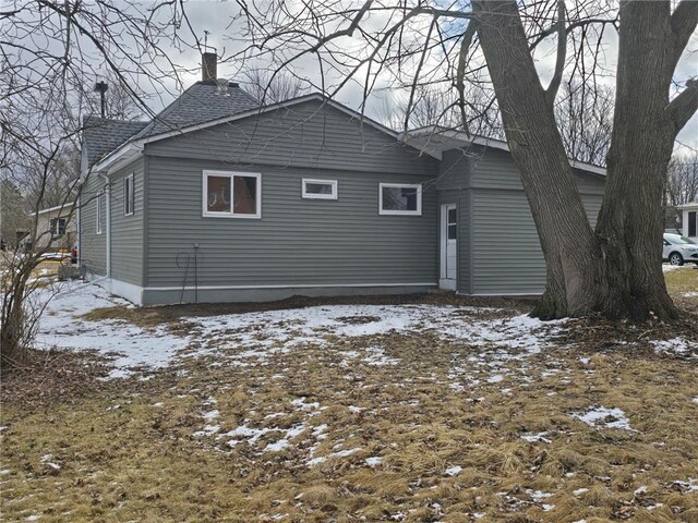 snow covered property with a chimney and a shingled roof