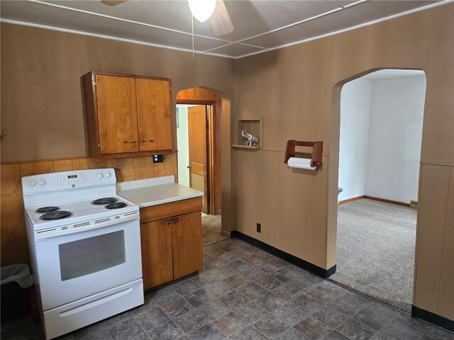 kitchen featuring brown cabinets, baseboards, arched walkways, and white electric range