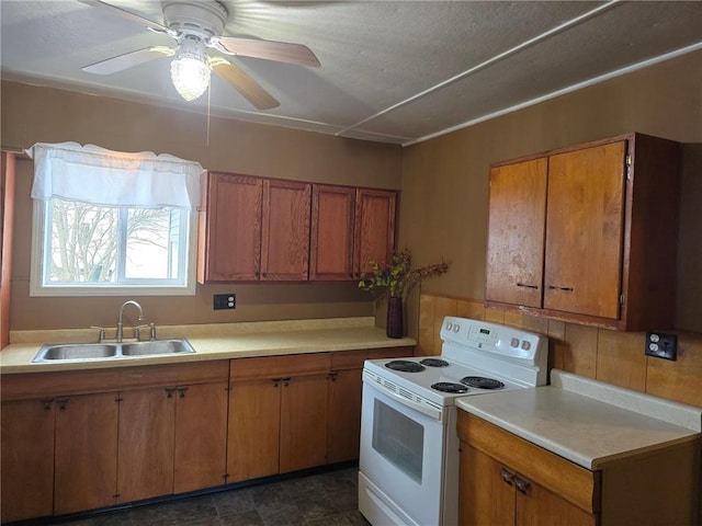 kitchen with a sink, light countertops, a ceiling fan, brown cabinets, and electric range