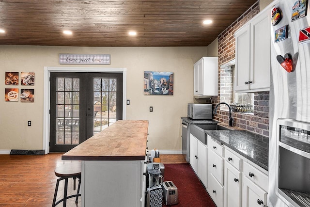3304 Nicolet Dr, Green Bay, WI 54311 - kitchen featuring wooden ceiling, a sink, white cabinetry, a kitchen bar, and stainless steel appliances