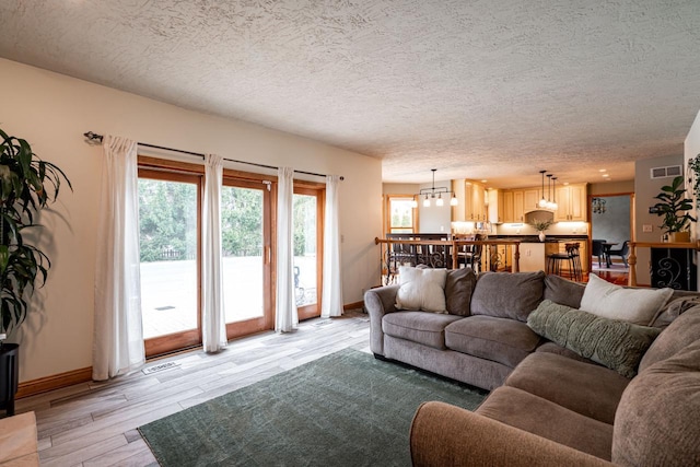 4824 Hampton Ct, Mount Pleasant, WI 53403 - living room featuring a textured ceiling, an inviting chandelier, light wood-style flooring, baseboards, and visible vents
