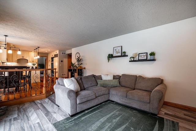 4824 Hampton Ct, Mount Pleasant, WI 53403 - living room featuring wood finished floors, a textured ceiling, a chandelier, baseboards, and visible vents