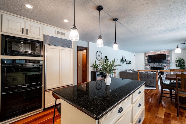 4824 Hampton Ct, Mount Pleasant, WI 53403 - kitchen featuring dark wood finished floors, black appliances, a textured ceiling, and a fireplace