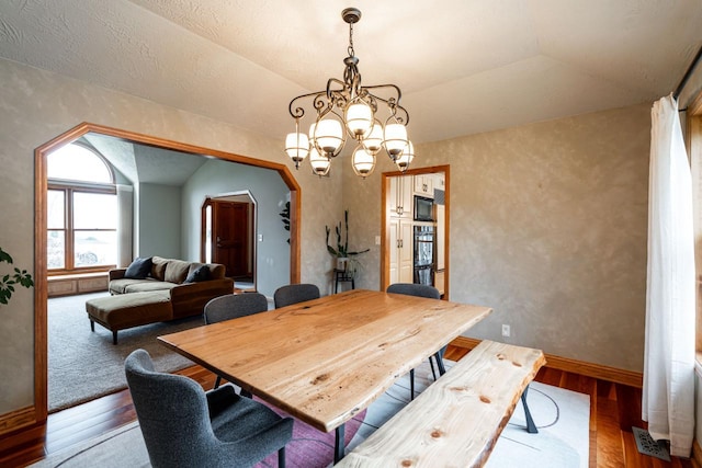 4824 Hampton Ct, Mount Pleasant, WI 53403 - dining area with vaulted ceiling, arched walkways, wood finished floors, and an inviting chandelier