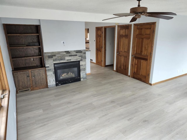 N9148 Sandy Lake Rd, Neshkoro, WI 54960 - unfurnished living room featuring light wood-type flooring, a stone fireplace, baseboards, and ceiling fan