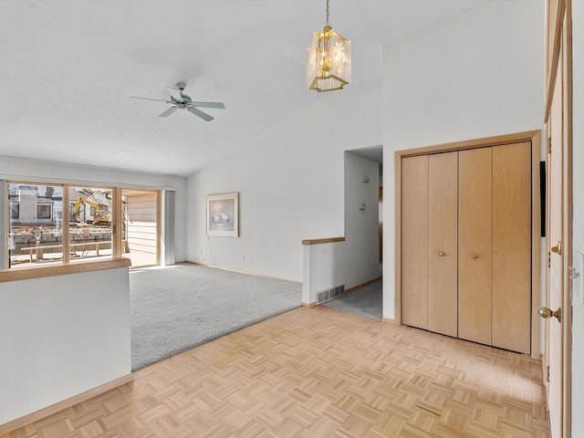 535 E Vine Ct, Sturgeon Bay, WI 54235 - unfurnished living room featuring high vaulted ceiling, ceiling fan with notable chandelier, baseboards, and visible vents