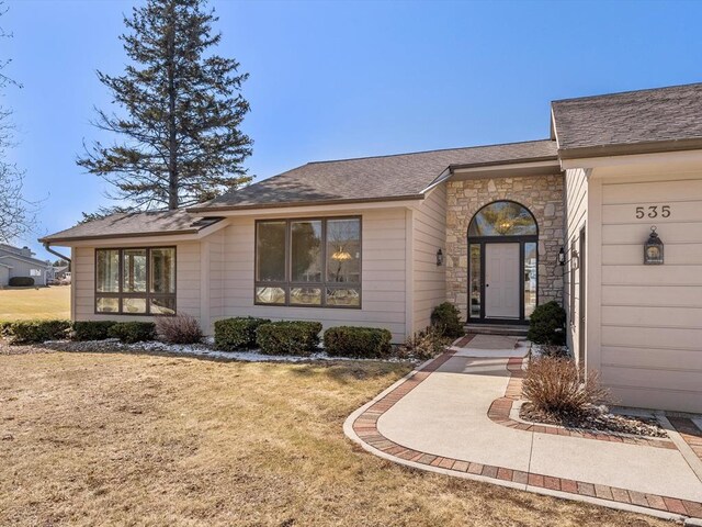 535 E Vine Ct, Sturgeon Bay, WI 54235 - view of front facade featuring a front lawn, a shingled roof, and stone siding
