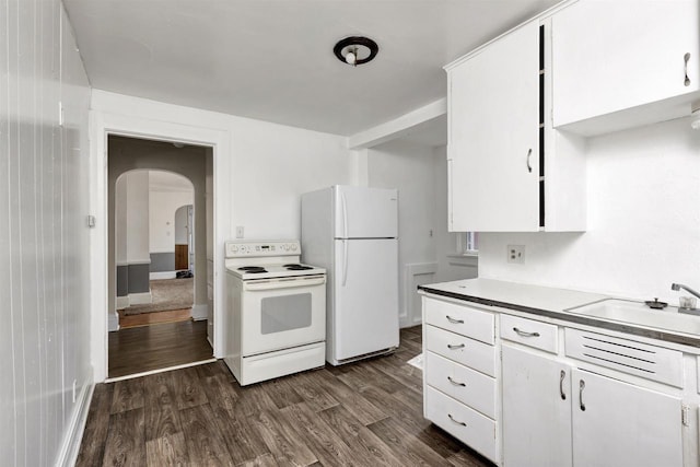 kitchen with dark wood finished floors, white appliances, arched walkways, white cabinets, and a sink