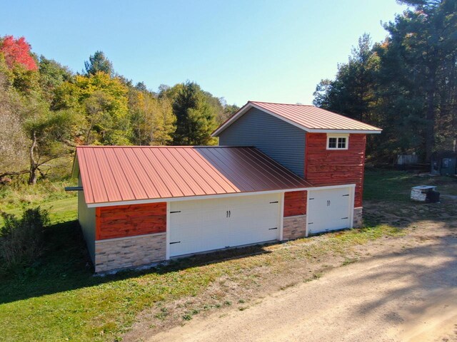 26350 Drake Ln, Cazenovia, WI 53924 - exterior space with stone siding, metal roof, a garage, and dirt driveway