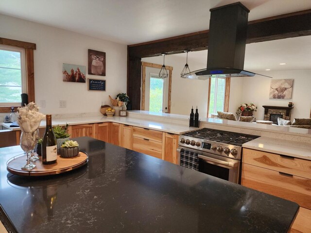 26350 Drake Ln, Cazenovia, WI 53924 - kitchen with high end stainless steel range oven, a stone fireplace, light brown cabinets, island range hood, and decorative light fixtures