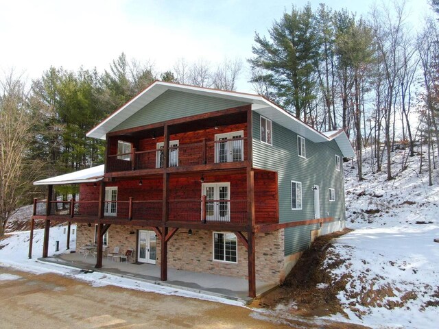 26350 Drake Ln, Cazenovia, WI 53924 - snow covered rear of property with french doors, stone siding, and a patio