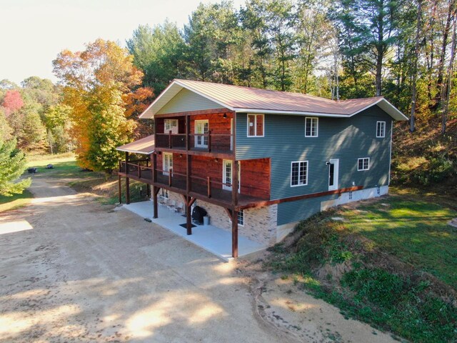 26350 Drake Ln, Cazenovia, WI 53924 - view of front facade with metal roof, a front lawn, a patio area, and dirt driveway