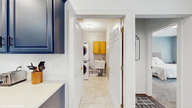 425 Maple Ln, Williams Bay, WI 53191 - clothes washing area with a sink, stacked washer and clothes dryer, cabinet space, and light tile patterned flooring