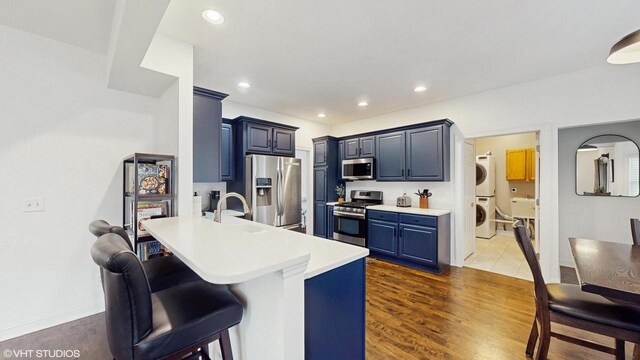 425 Maple Ln, Williams Bay, WI 53191 - kitchen with light countertops, a kitchen breakfast bar, a peninsula, stacked washer and clothes dryer, and stainless steel appliances