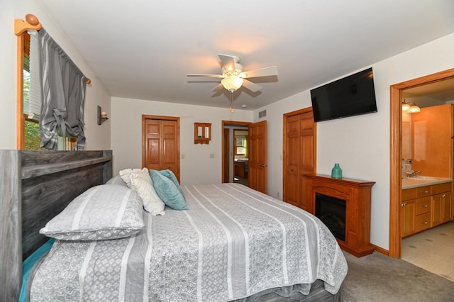 2855 N Shore Dr, Delavan, WI 53115 - bedroom with ceiling fan, connected bathroom, visible vents, light carpet, and a fireplace