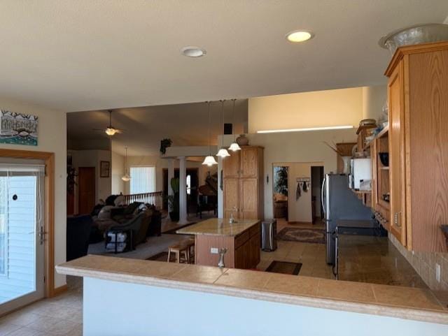 2026 Stonehaven Dr, Sun Prairie, WI 53590 - kitchen with a ceiling fan, light countertops, brown cabinetry, and a kitchen island