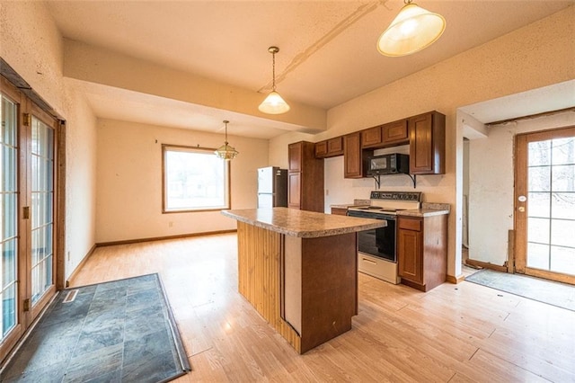 kitchen featuring freestanding refrigerator, plenty of natural light, black microwave, and range with electric cooktop