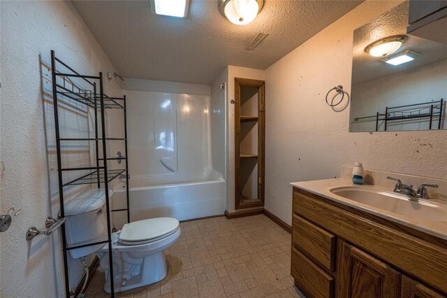 bathroom with toilet, vanity, a textured ceiling, baseboards, and a textured wall