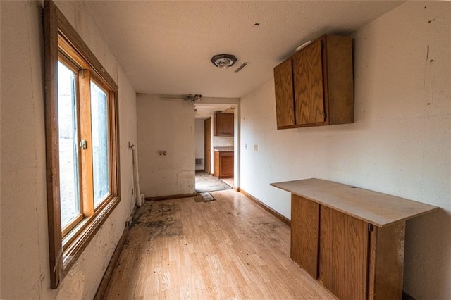 interior space with a wealth of natural light, visible vents, brown cabinetry, and light wood-style floors