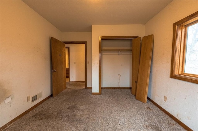 unfurnished bedroom featuring baseboards, a closet, carpet floors, and a textured wall