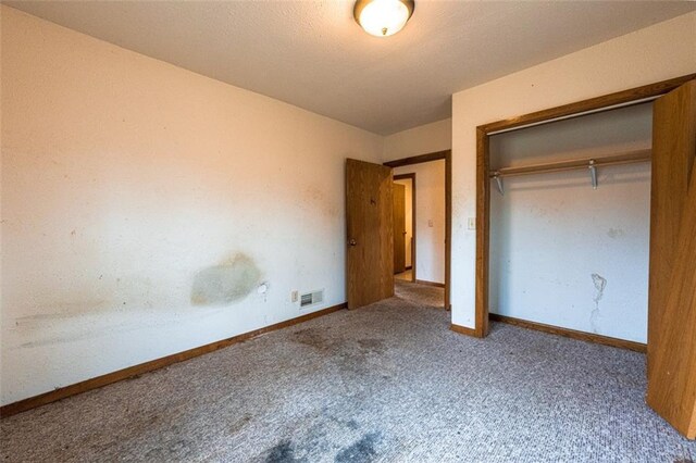 unfurnished bedroom with a closet, carpet floors, visible vents, and baseboards