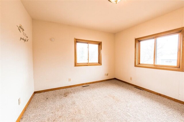 empty room with carpet floors, baseboards, and visible vents
