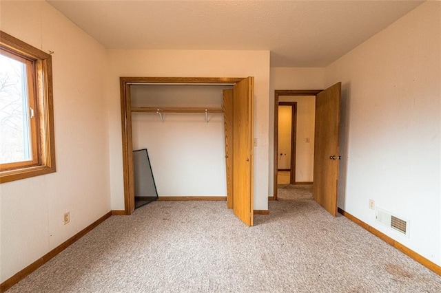 unfurnished bedroom with baseboards, visible vents, a closet, and carpet floors