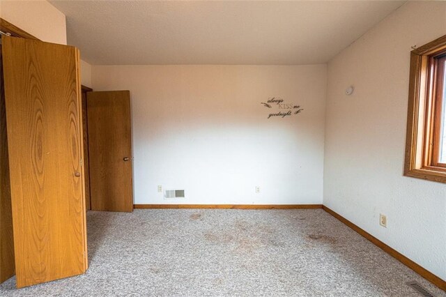 empty room with baseboards, carpet floors, and visible vents