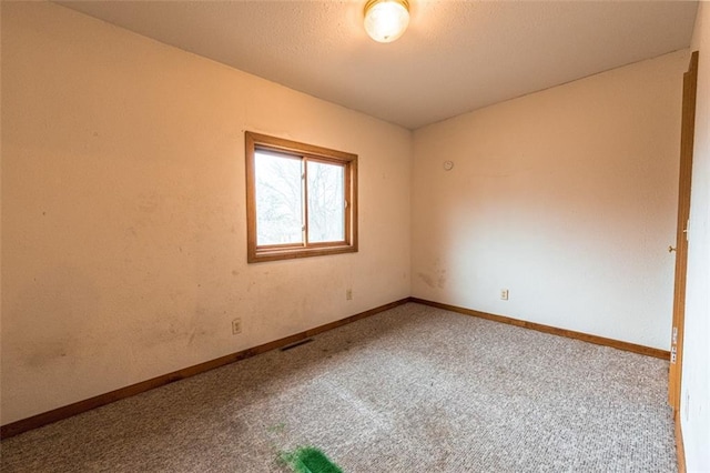 empty room with baseboards, visible vents, carpet flooring, and a textured ceiling