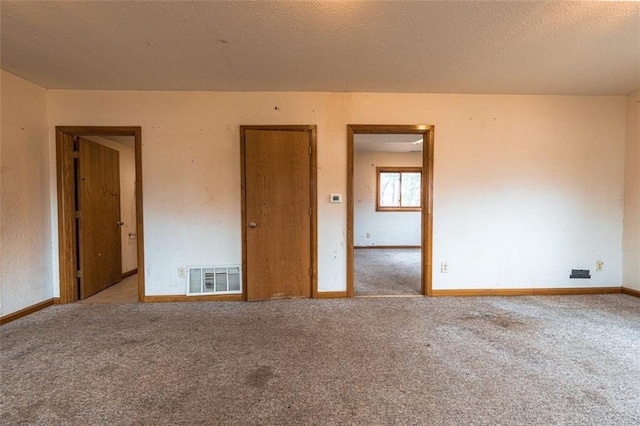 spare room featuring carpet floors, a textured ceiling, baseboards, and visible vents