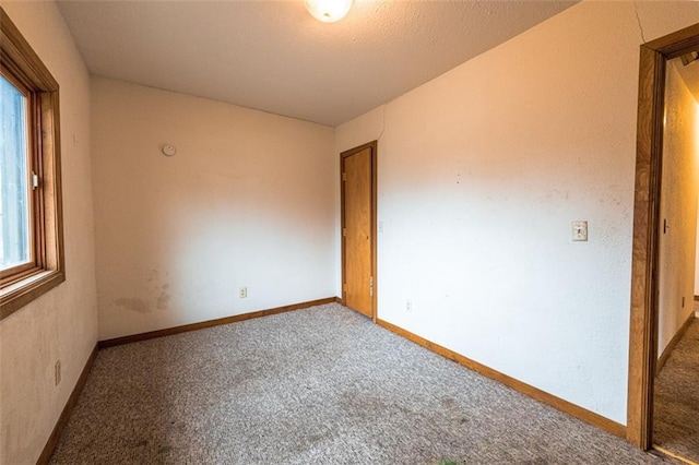 unfurnished room with baseboards and carpet flooring