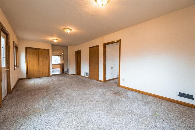 unfurnished bedroom featuring baseboards, visible vents, carpet floors, and a textured ceiling