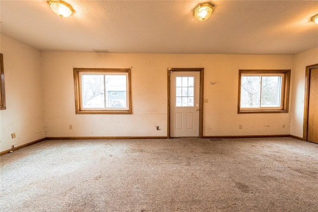 spare room featuring baseboards, carpet flooring, and a textured ceiling