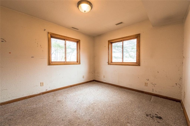 carpeted spare room featuring baseboards and visible vents