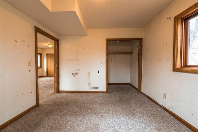 unfurnished bedroom with carpet flooring, baseboards, a closet, and visible vents
