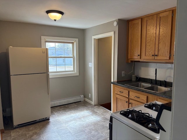 1006 Lulu Ave, Crivitz, WI 54114 - kitchen featuring white appliances, a sink, dark countertops, brown cabinetry, and baseboard heating