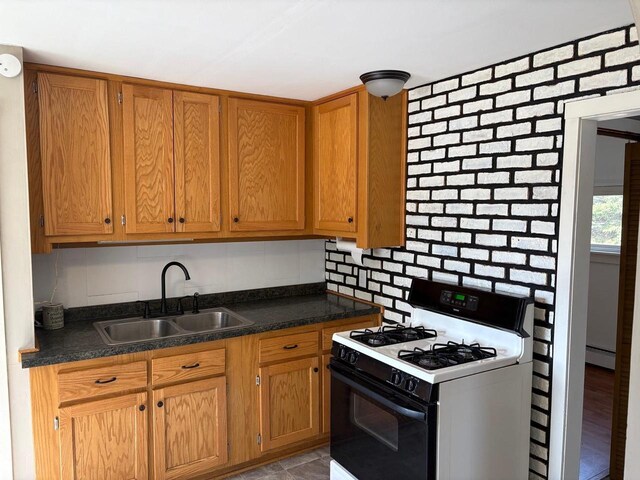 1006 Lulu Ave, Crivitz, WI 54114 - kitchen featuring a sink, white range with gas cooktop, brown cabinets, baseboard heating, and dark countertops