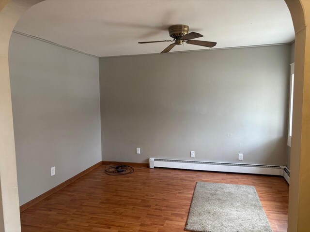 1006 Lulu Ave, Crivitz, WI 54114 - spare room with a baseboard radiator, wood finished floors, arched walkways, and a ceiling fan