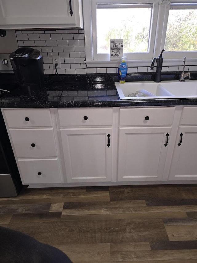 25290 Foothill Ave, Tomah, WI 54660 - kitchen featuring a sink, dark wood finished floors, dark countertops, white cabinets, and decorative backsplash