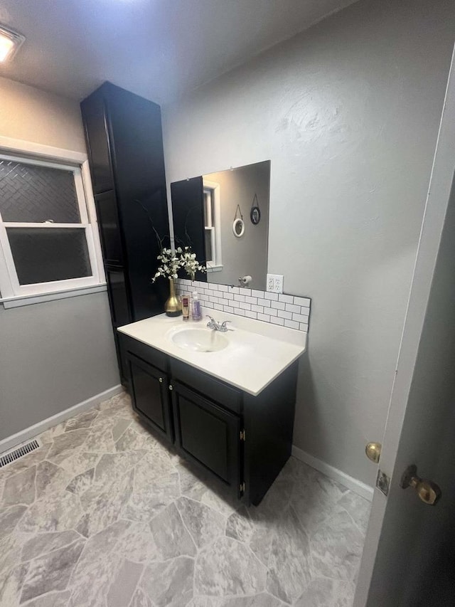 25290 Foothill Ave, Tomah, WI 54660 - bathroom featuring baseboards, visible vents, decorative backsplash, and vanity