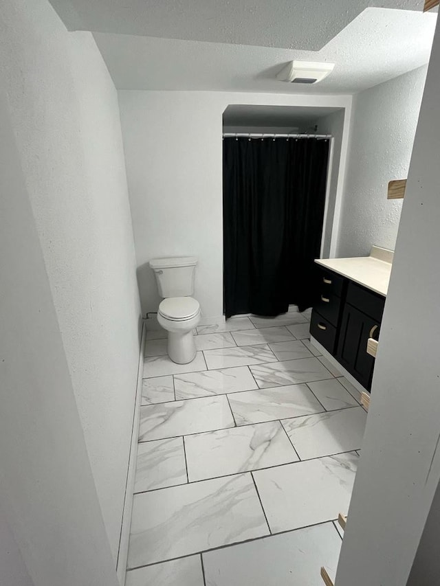 25290 Foothill Ave, Tomah, WI 54660 - bathroom featuring vanity, toilet, a textured wall, a textured ceiling, and marble finish floor
