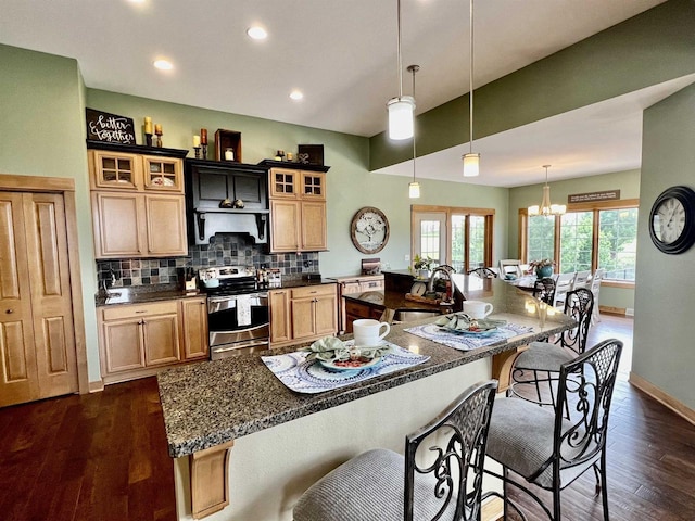 kitchen with a sink, tasteful backsplash, stainless steel electric range, a kitchen bar, and dark wood-type flooring