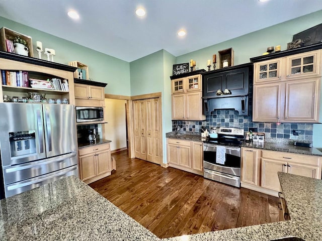 kitchen with appliances with stainless steel finishes, tasteful backsplash, dark wood-type flooring, and glass insert cabinets