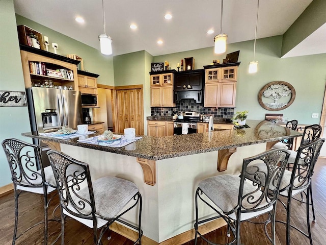 kitchen with glass insert cabinets, decorative backsplash, appliances with stainless steel finishes, dark wood-type flooring, and a breakfast bar area