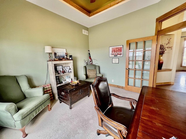 carpeted office featuring a tray ceiling, visible vents, and baseboards